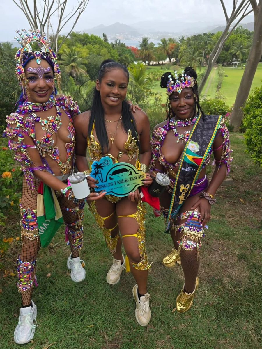 Two masqueraders in full carnival costume holding the King J’s sign